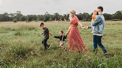 Family holding hands walking through a field